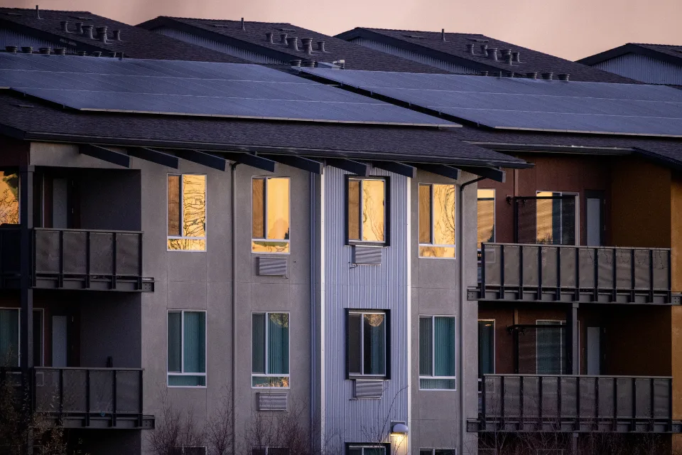 Mehrfamilienhaus mit Solarmodulen auf dem Dach in der Abenddämmerung